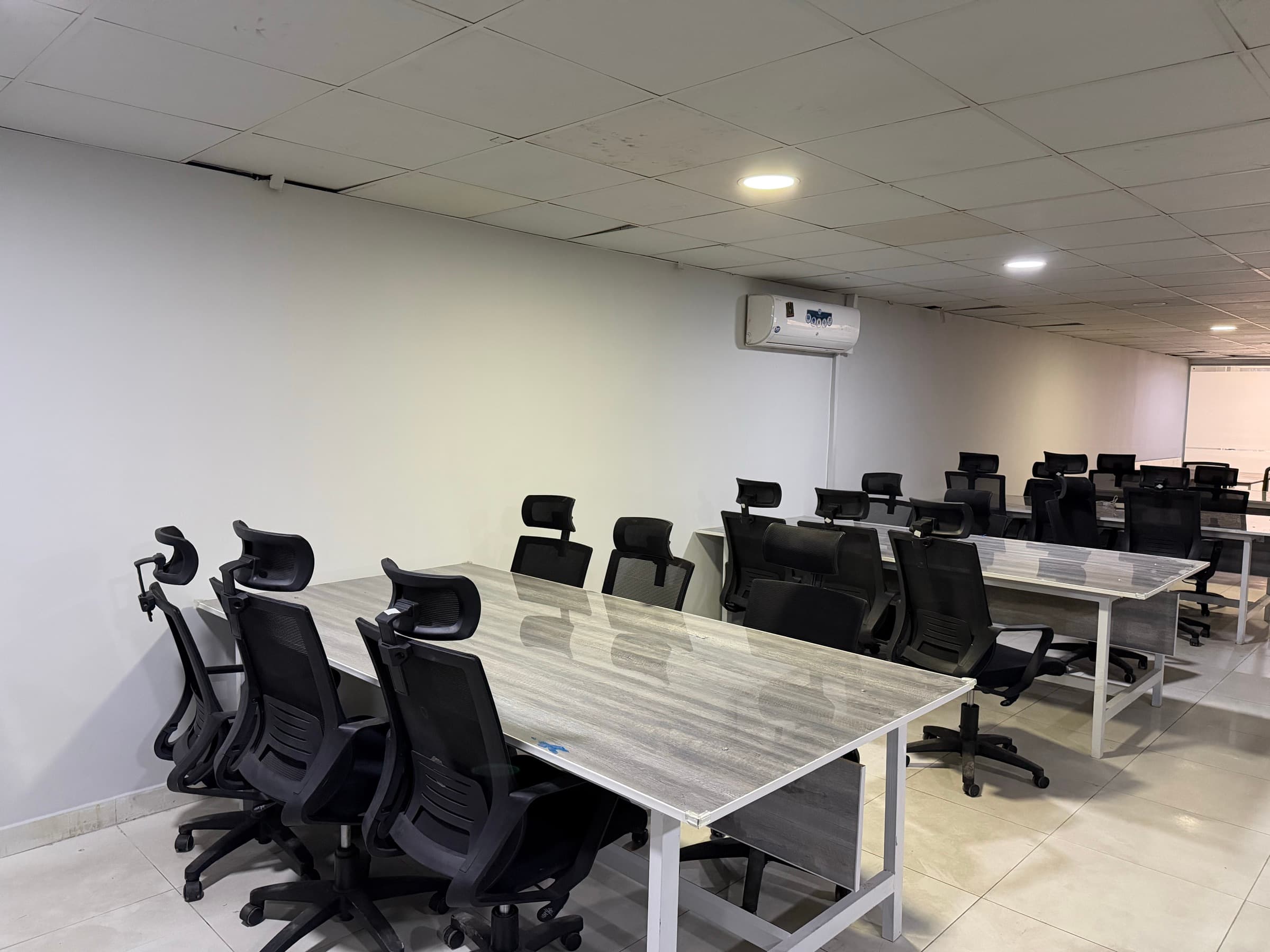 Desks running the length of the floor, with an air conditioning unit on the wall and further workstations behind.